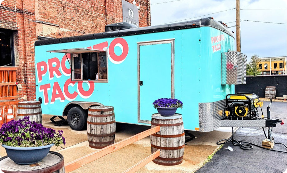 Food truck set up with its window open in front of a brewery building