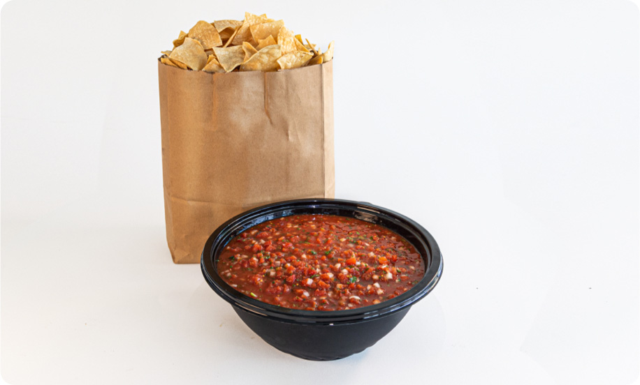 Big bag of chips next to a big bowl of salsa