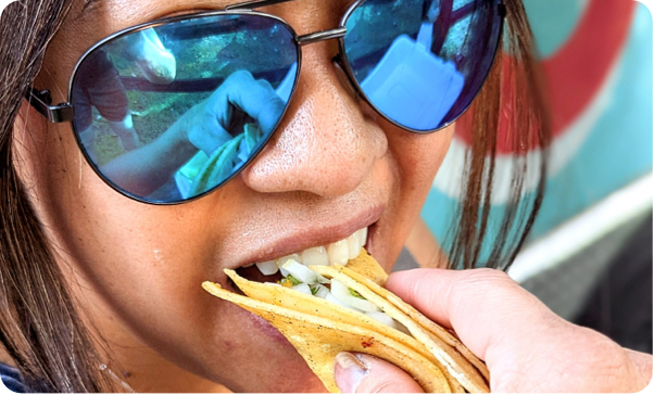 Closeup of woman with blue mirror sunglasses eating taco