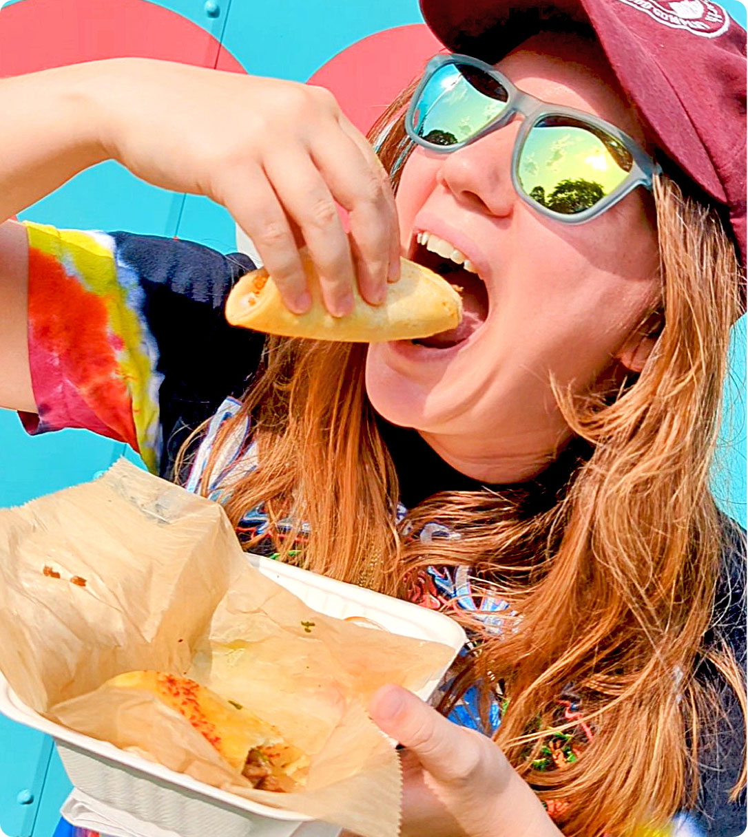 Woman in mirrored visor-style sunglasses eating taco