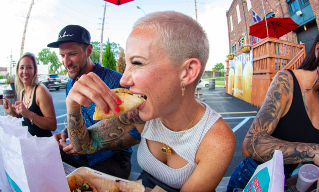 Fish eye lens photo of smiling people eating Pronto Taco food at outdoor table