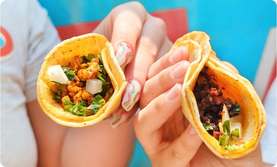 Closeup of two hands holding two tacos