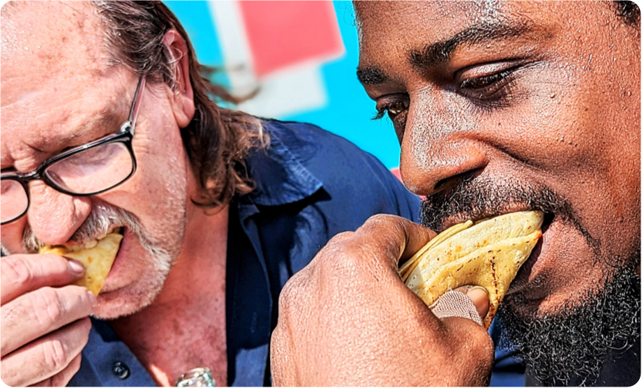Closeup of two men eating tacos next to each other