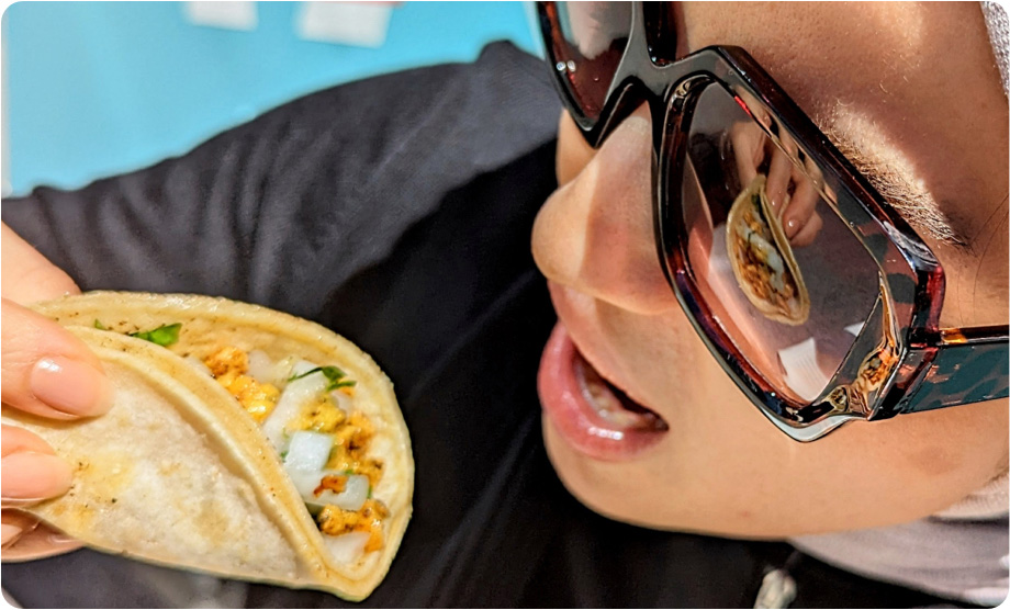 Closeup of white woman with squareish mirror sunglasses eating taco